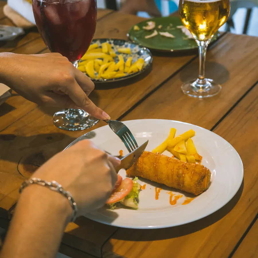 Dos personas comparten un plato con patatas fritas en una mesa de terraza