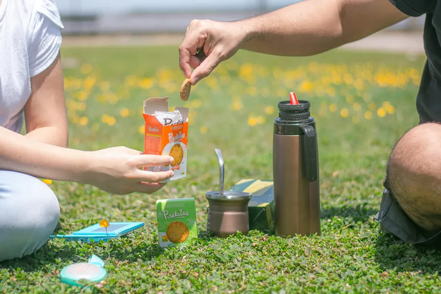 Dos personas prueban unas galletas en un picnic sobre el césped