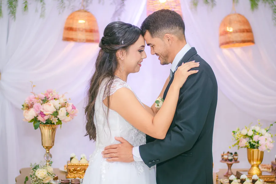 Los novios se abrazan frente a frente bajo lámparas de mimbre