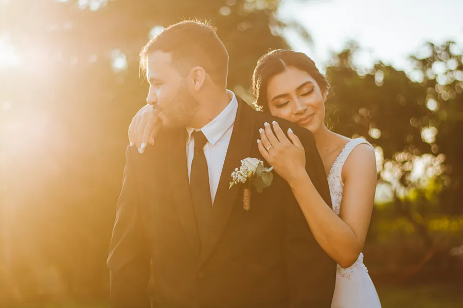 Una novia apoya la cabeza en el hombro del novio a contraluz del atardecer