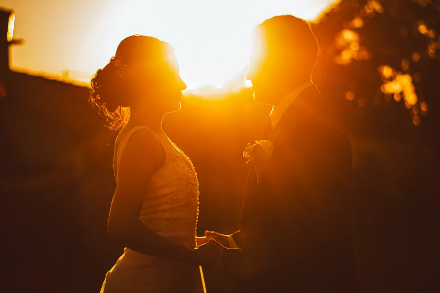 Silueta de los novios a punto de besarse con el sol detrás