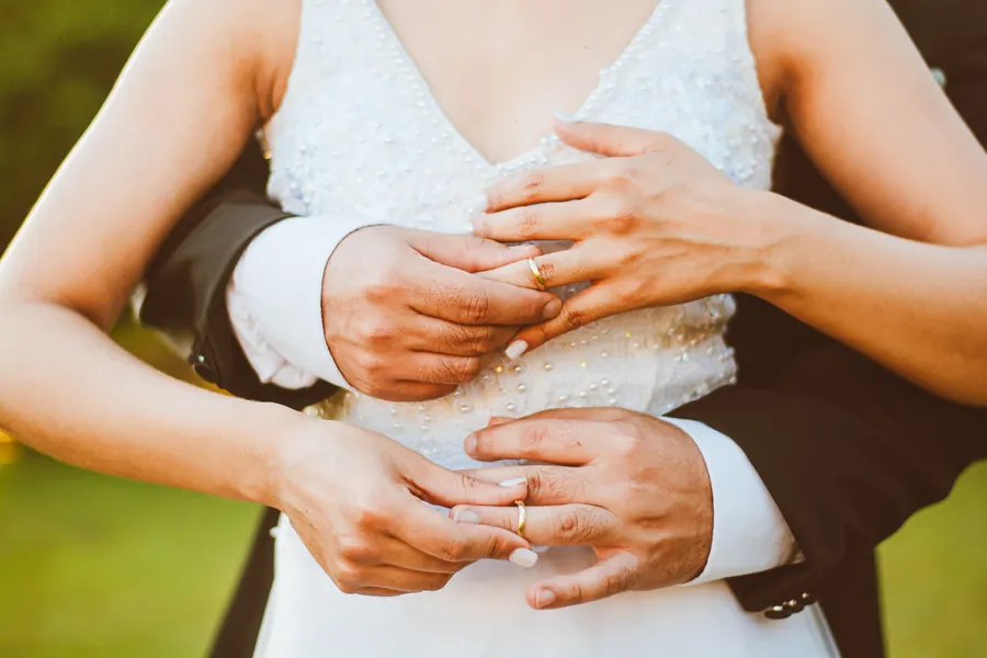 Las manos de los novios entrelazadas, con los anillos a la vista