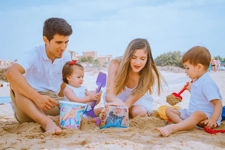 Una familia juega con cubos y palas en la arena de la playa