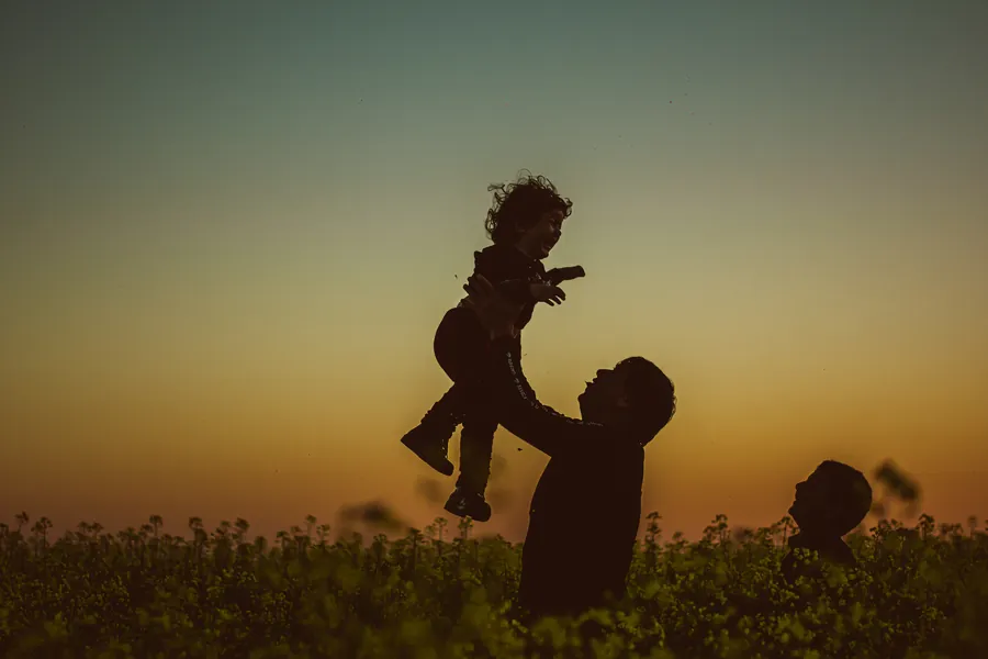 Silueta de un padre lanzando a su hijo al aire al atardecer